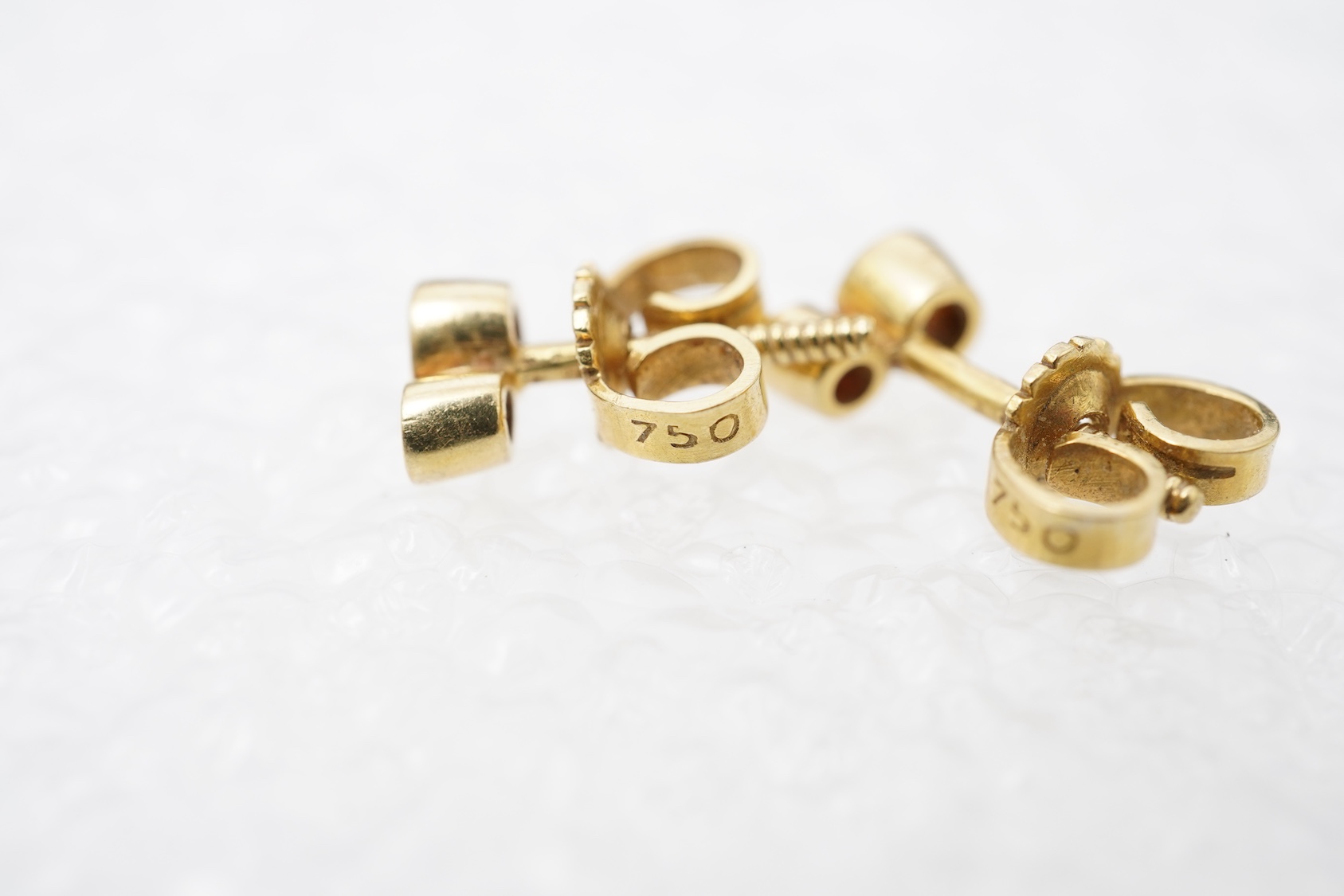 A pair of ruby and diamond stud earrings, set with brilliant-cut diamonds totalling approximately 0.15 carats, surmounted by circular-cut rubies, in gold collet settings, length 0.6cm each, post fittings